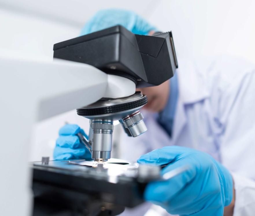 Een microscoop met erachter een laborant